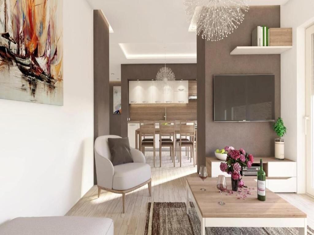 Ein modernes Wohnzimmer mit einer Couch, einem Essbereich und einer Küche im Hintergrund.