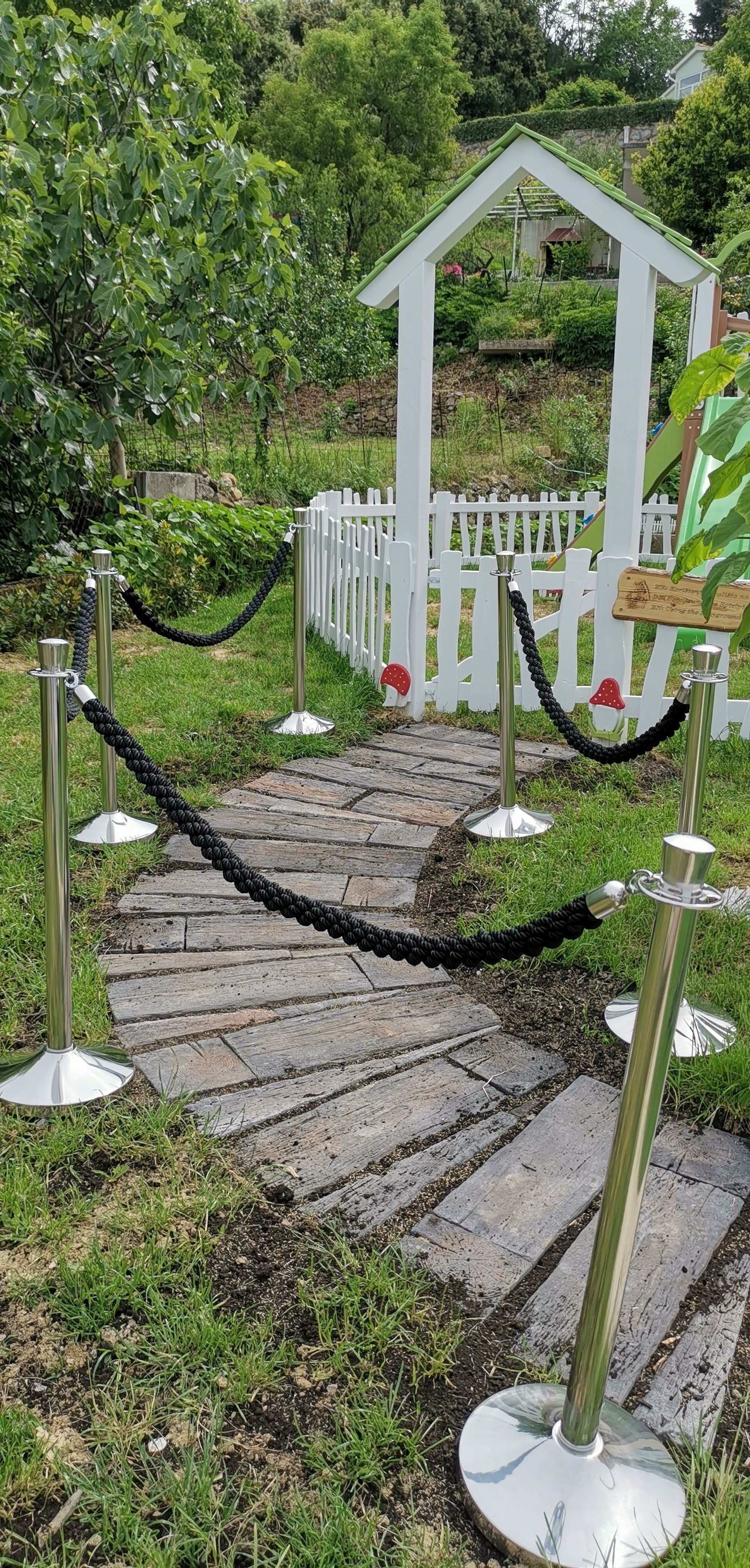 A garden pathway with a white fence and a small white gazebo.