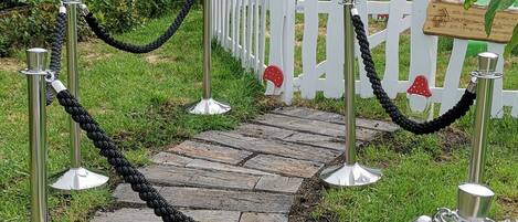 A garden pathway with a white fence and a small white gazebo.