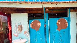 A rustic bathroom with a sink and two blue doors with handprints. - Puerto Caracol Isla Múcura (Isla Mucura)