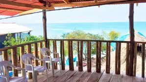 A wooden deck with plastic chairs, overlooking a beach with a clear view of the ocean. - Puerto Caracol Isla Múcura (Isla Mucura)