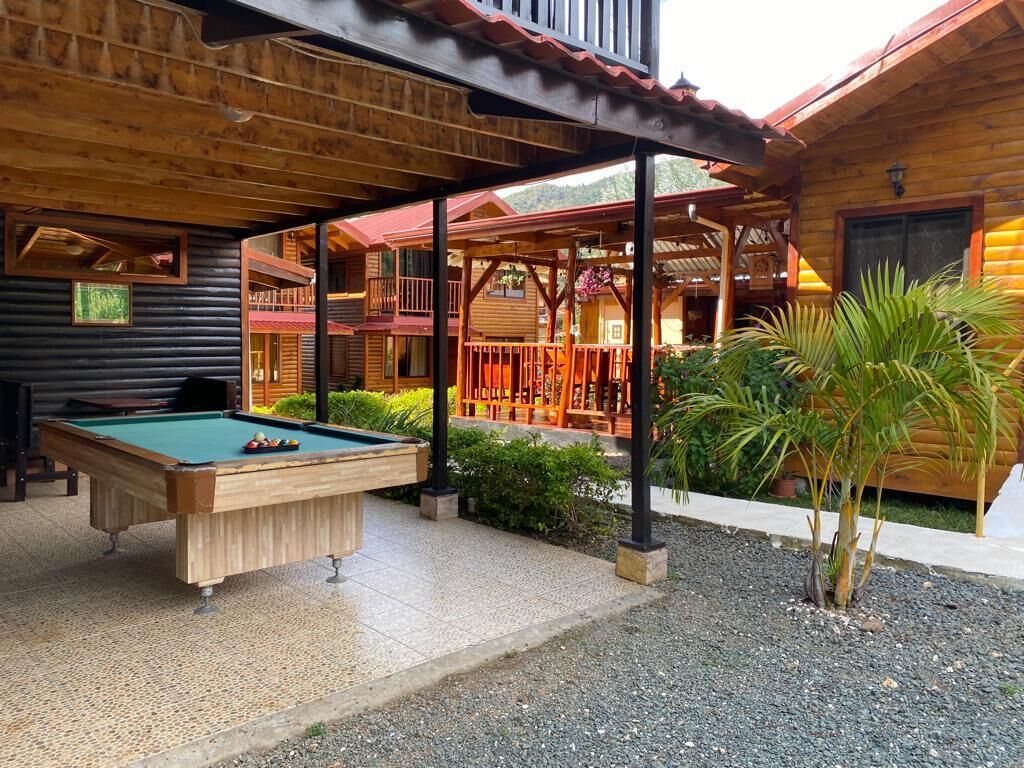 Een houten chalet met biljart, terras en overdekte patio.