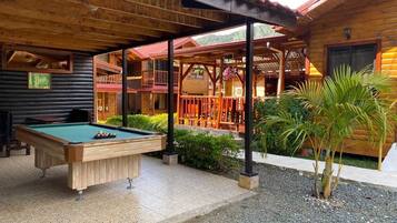 Een houten chalet met biljart, terras en overdekte patio.