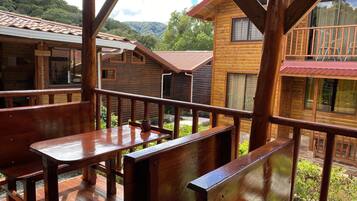 A wooden cabin with a balcony, a reception area, and a view of the surrounding forest.