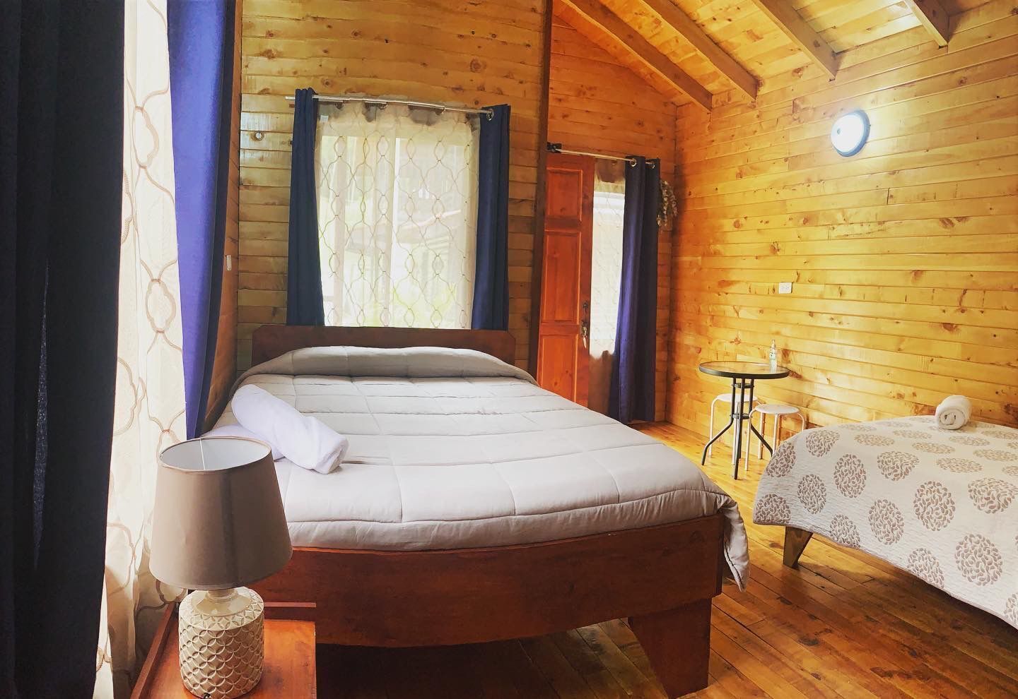 Une pièce dans un chalet en bois, comprenant un lit, une petite table et une chaise.