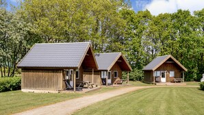Two wooden cabins with pitched roofs, each featuring a picnic table and a bench. - Jelling Familie Camping (Jelling)