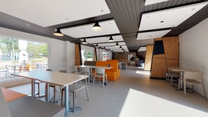 A modern cafeteria with high tables and chairs, wooden partitions, and pendant lighting. - Jelling Familie Camping (Jelling)