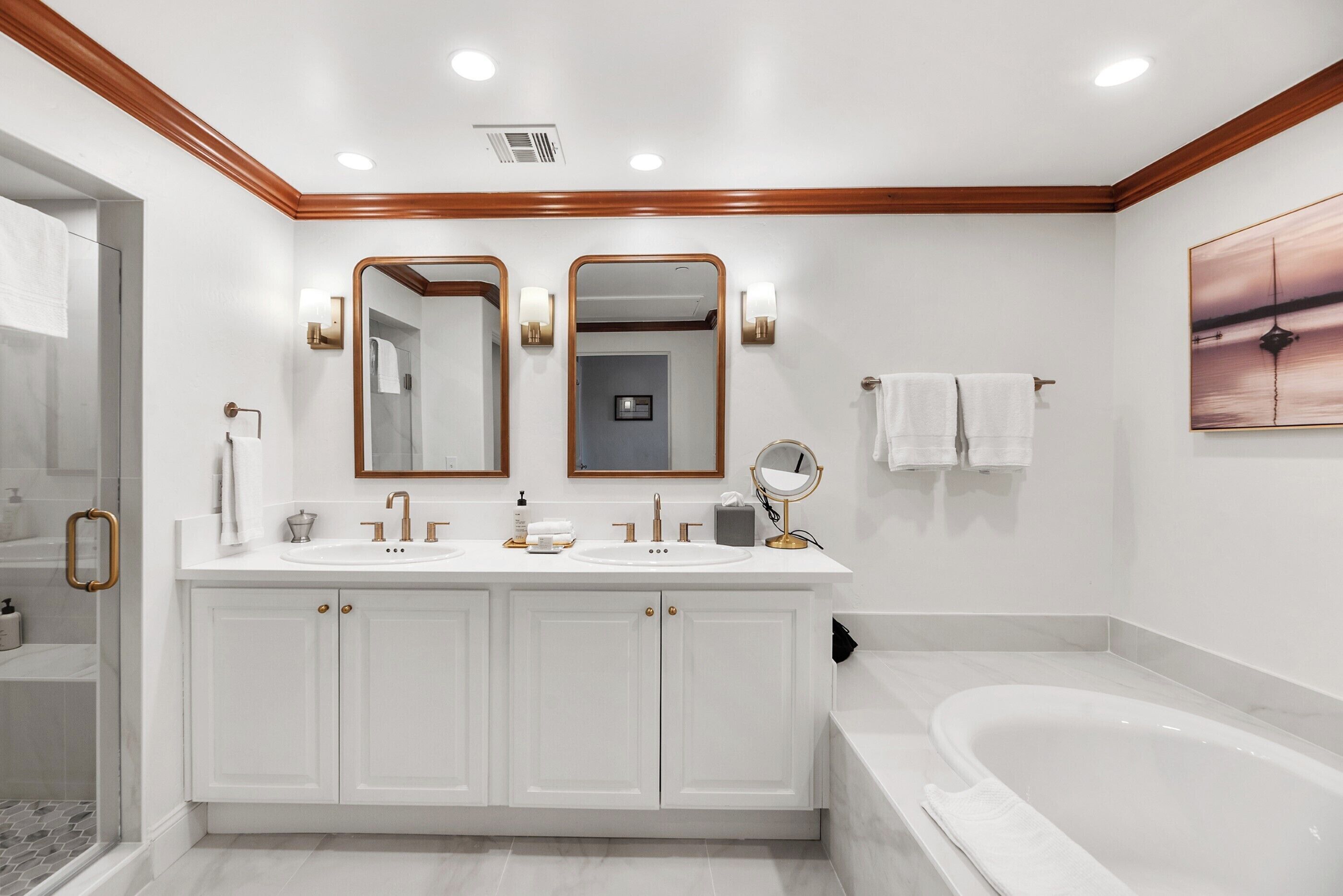 A modern bathroom with a double vanity, a large bathtub, and two wall-mounted mirrors.