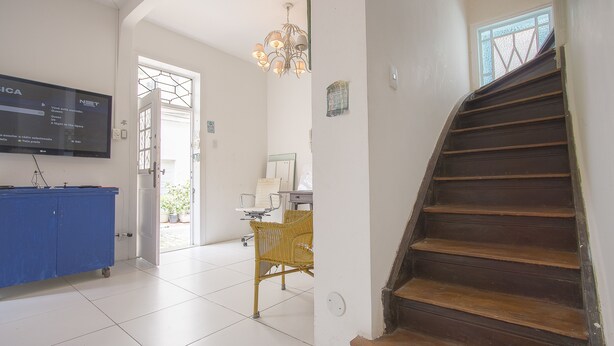 A staircase leading to a second floor, a blue storage unit, a wicker chair, and a television displaying a menu. - LineRio Praia de Copacabana 372 (Rio de Janeiro)