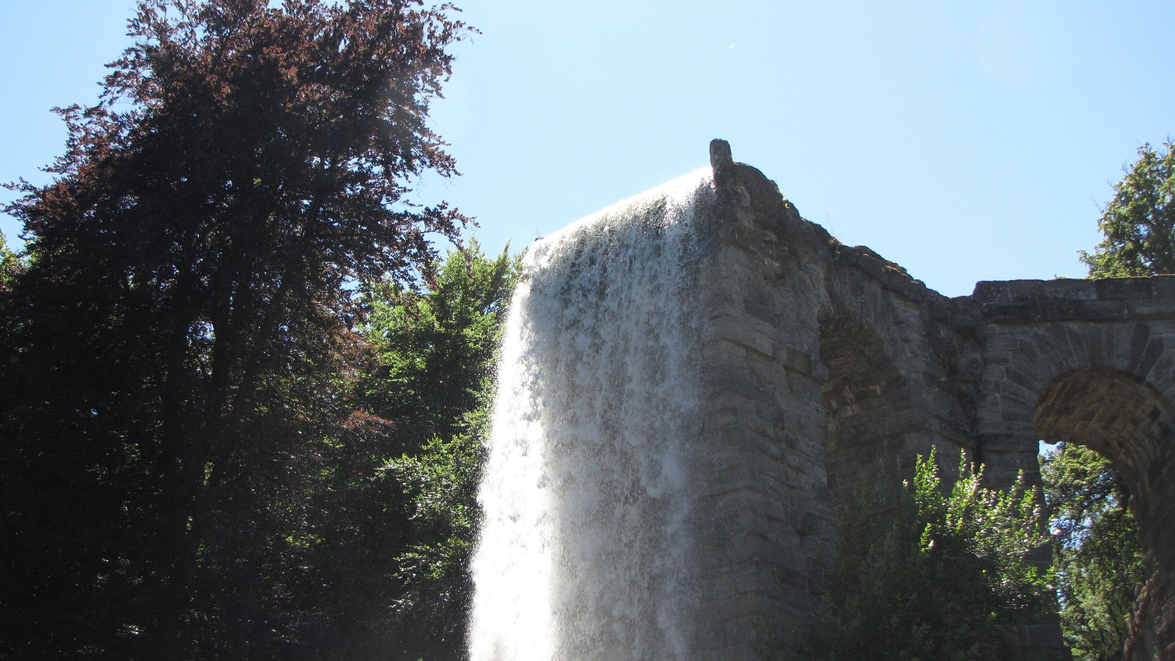 A waterfall cascading over a stone structure with an archway.