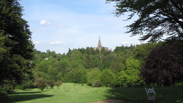 Un terrain de golf avec un bâtiment situé au loin, sur une colline.