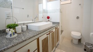 A modern bathroom with a white sink, two faucets, a mirror, and a toilet. - LineRio Praia de Copacabana 370.374 (Rio de Janeiro)