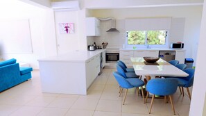 A modern kitchen with white cabinets, a central island, and blue chairs.