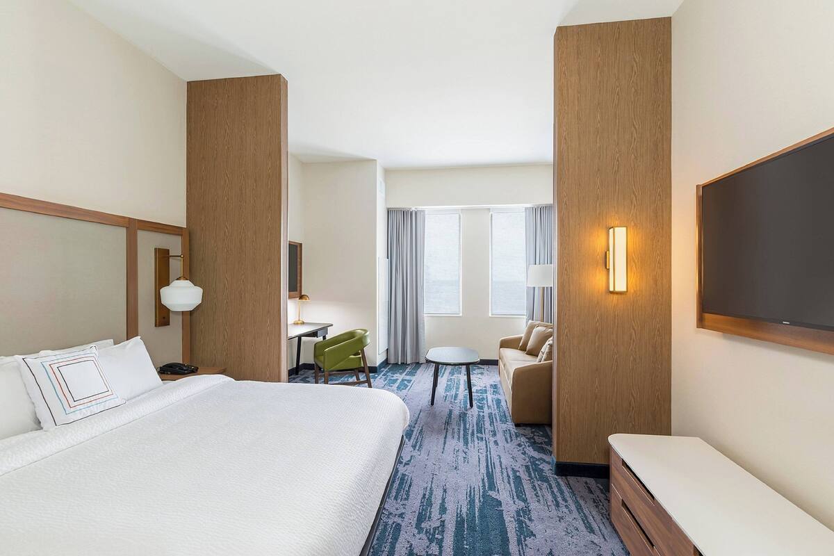 Une chambre d’hôtel avec un grand lit, un bureau, une chaise, un canapé et un téléviseur.