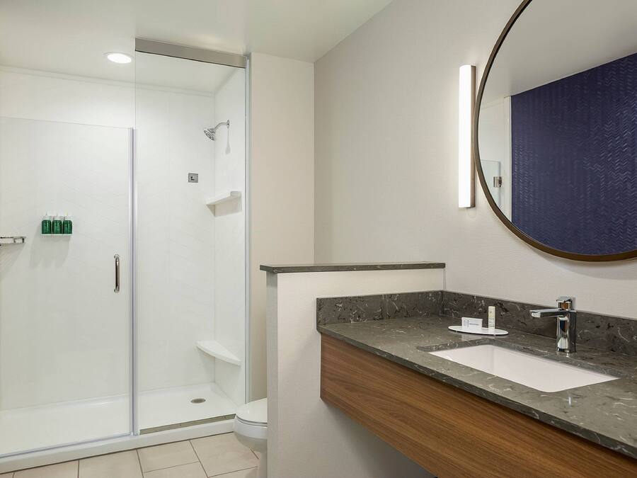 Une salle de bain moderne avec une douche à parois de verre, un comptoir en marbre et un grand miroir.