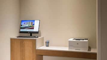 Un petit espace de bureau comprenant un bureau, un écran d’ordinateur et une imprimante.