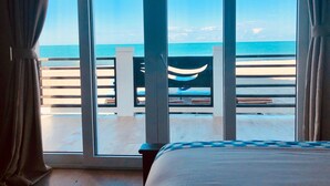 A room with a large window overlooking a beach. - Luxury Beachfront Cabana with swim up pool bar (Placencia)