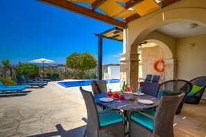 A rooftop terrace with a pool, outdoor seating, and a table set for dining. - Stunning 3 bedroom villa 'BZ01' with private pool, stunning views, communal pool and resort facilities, Zephyros Village on Aphrodite Hills Re (Kouklia)