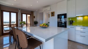 A modern kitchen with a central island, white cabinetry, and a view to the outside. - Stunning 3 bedroom villa 'BZ01' with private pool, stunning views, communal pool and resort facilities, Zephyros Village on Aphrodite Hills Re (Kouklia)