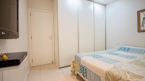 Une chambre à coucher avec un lit, une armoire et un téléviseur posé sur un meuble.