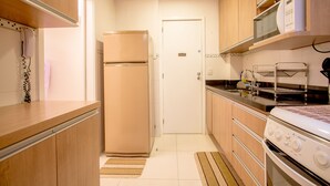 Une cuisine de taille réduite, dotée de meubles de rangement en bois, d’un réfrigérateur, d’un four à micro-ondes et d’une cuisinière.