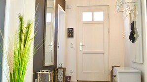 A modern hallway with a white door, a black rug, and a small white cabinet.