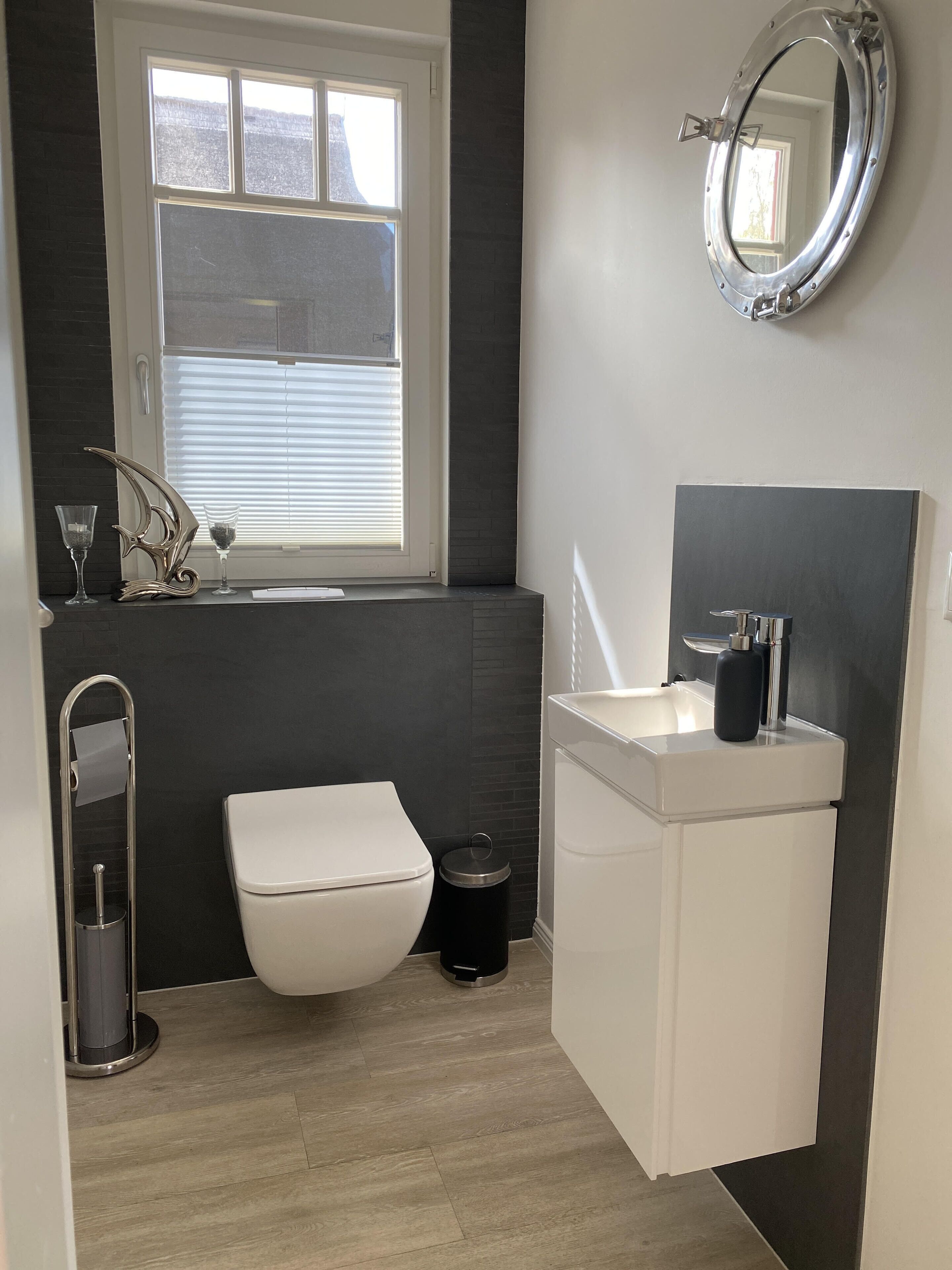A modern bathroom with a toilet, sink, and window.