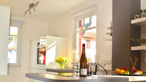 A modern kitchen with a central island, a built-in oven, and a window providing natural light.