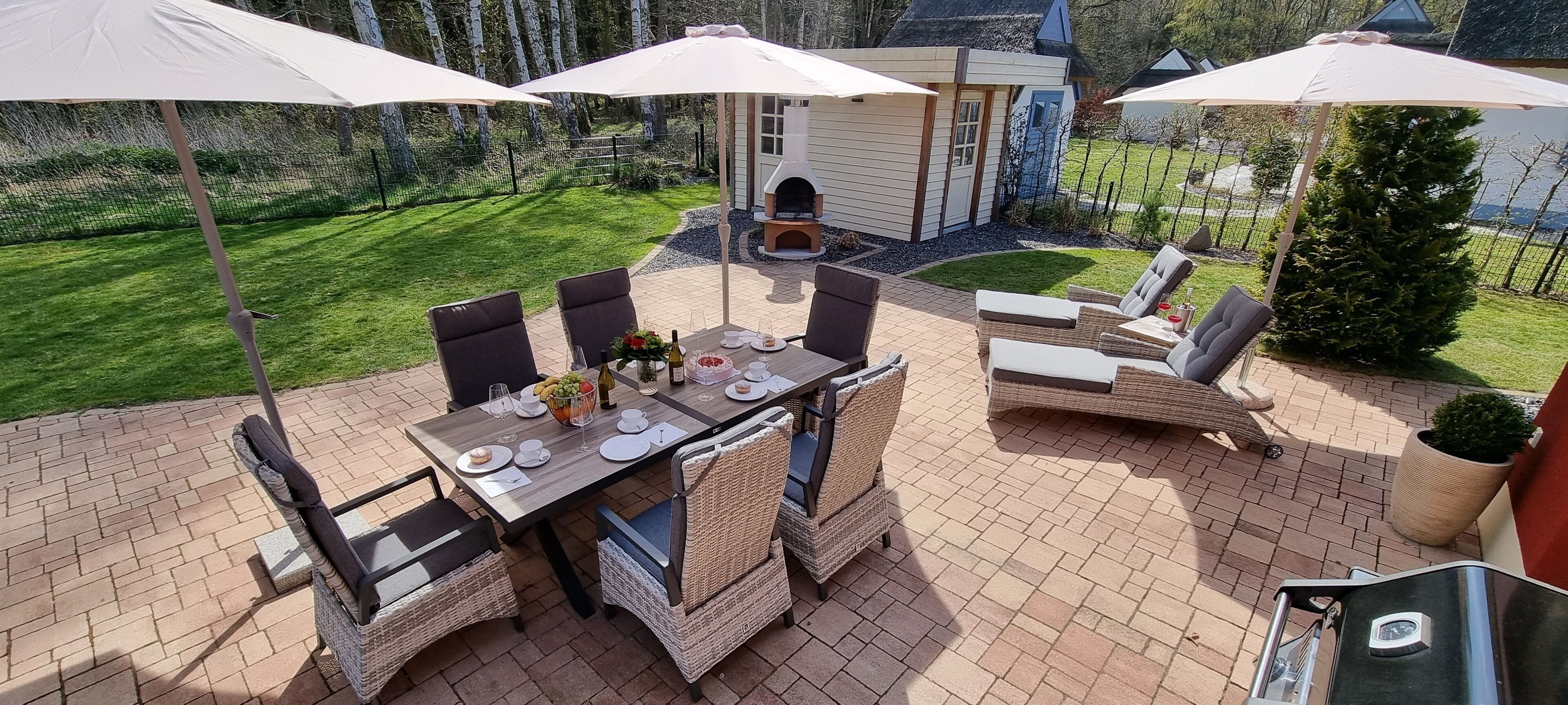 Une terrasse extérieure avec une table à manger, des chaises et des parasols.