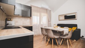 Une cuisine moderne avec un coin repas, comprenant un plan de travail en bois, une table à manger avec des chaises, un canapé noir avec des coussins jaunes et un miroir au mur.