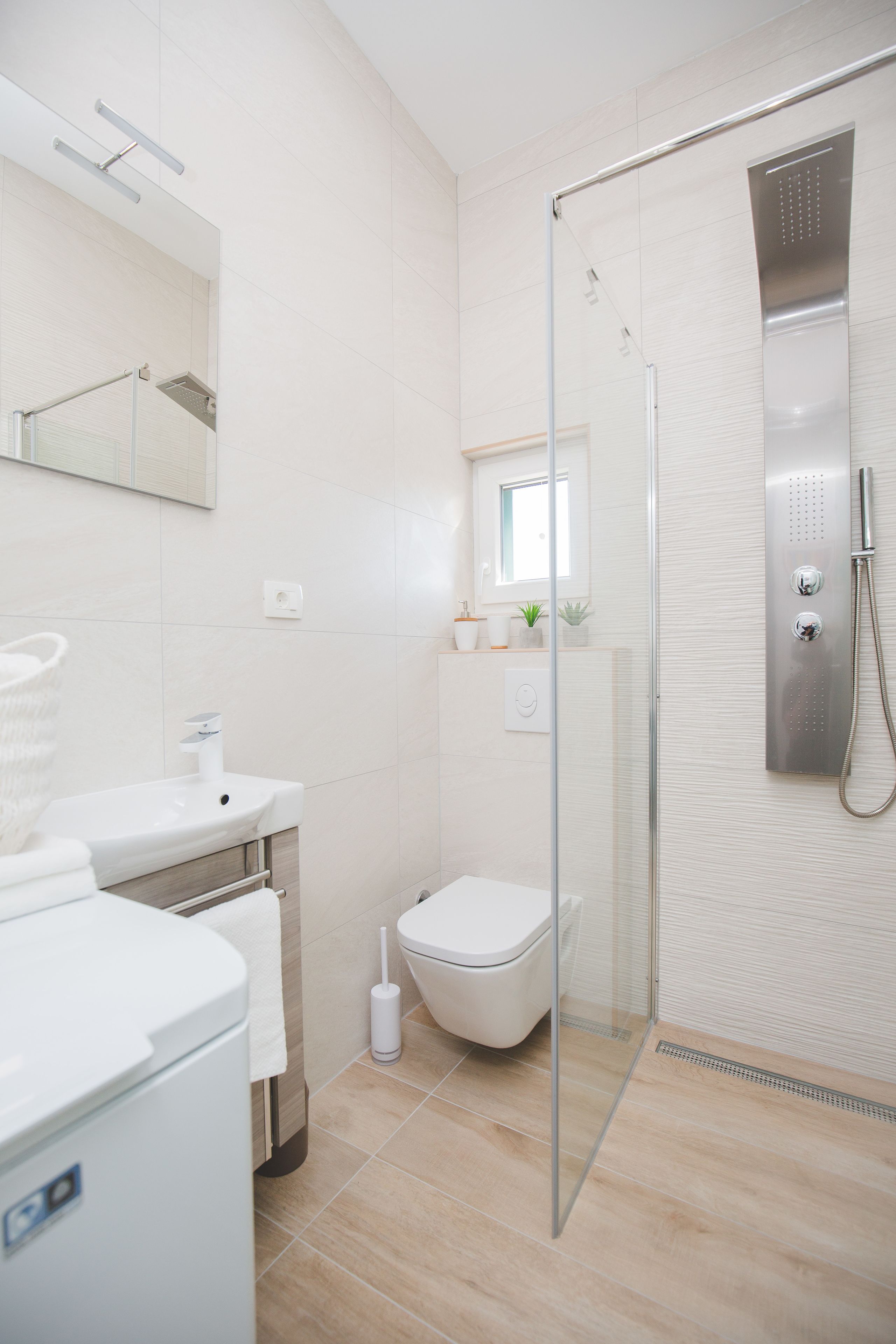 Ein modernes Badezimmer mit Duschkabine aus Glas, einem weißen Waschbecken und einer Toilette.