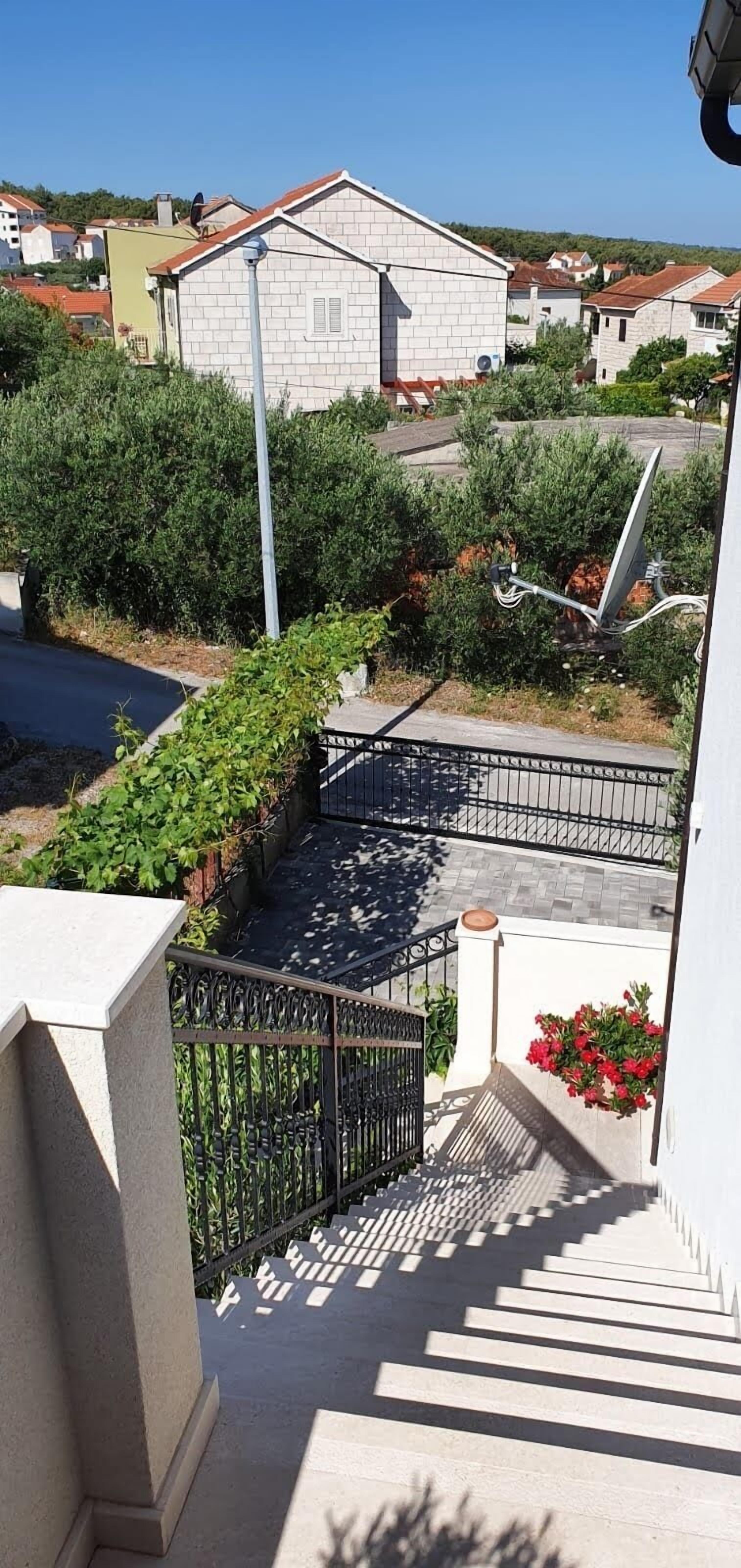 A residential area with a white building, a paved road, and a metal gate.