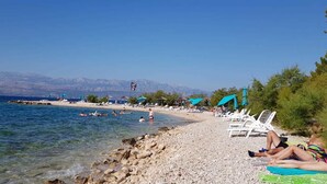 Une plage avec une eau claire, un rivage rocheux et des parasols.