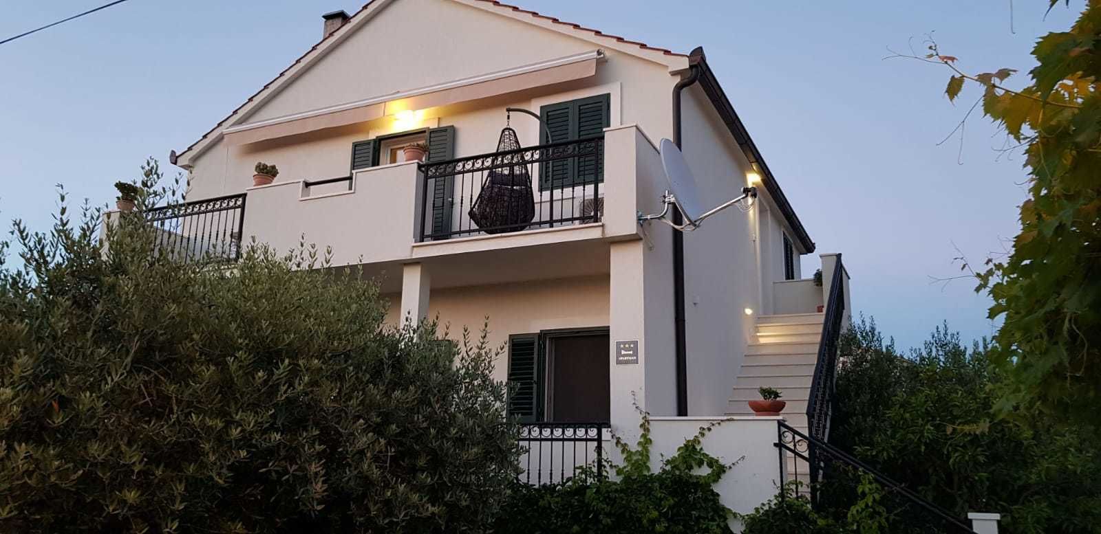 A two-story building with a balcony, a satellite dish, and a staircase leading to the entrance.