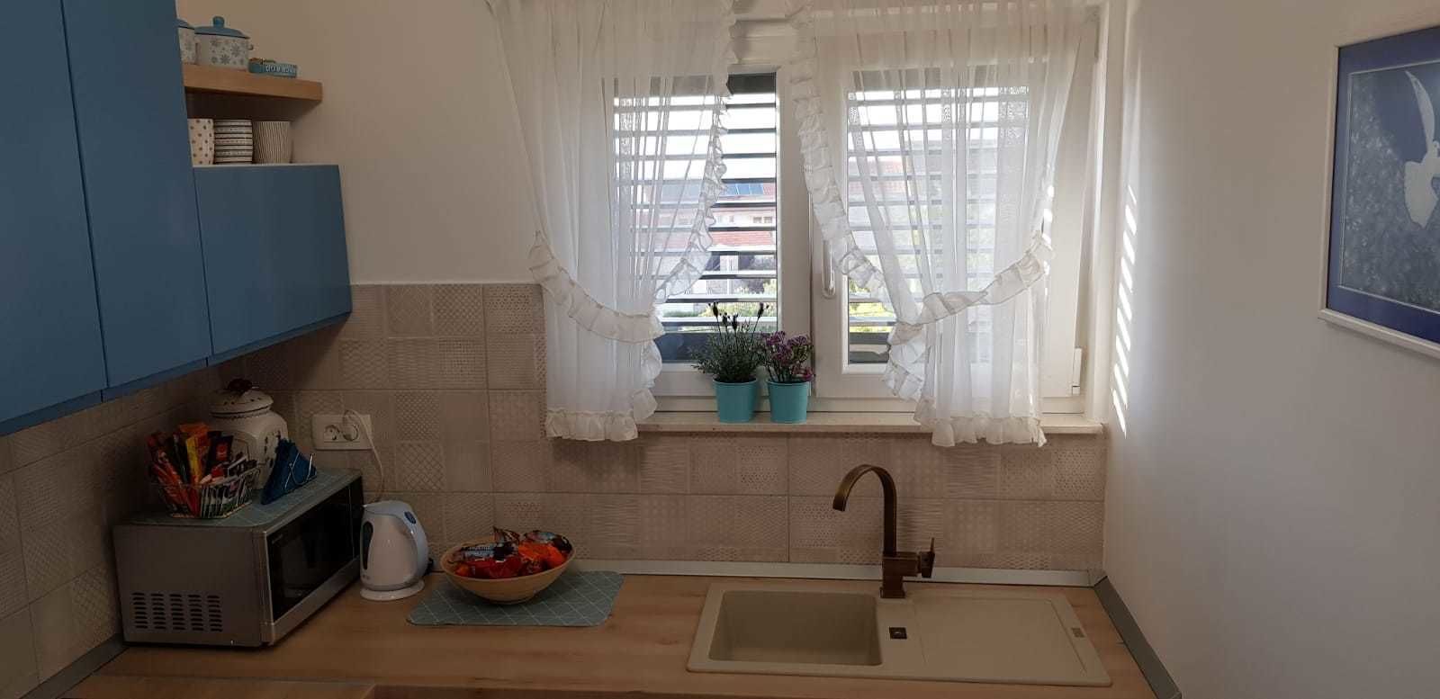 A compact kitchen with a microwave, kettle, and a bowl of fruit on the counter.