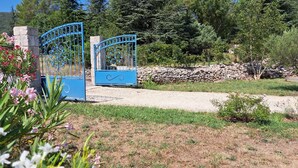 Un jardín con un camino de grava que lleva a una puerta azul.