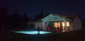 Une maison avec une piscine, de nuit.