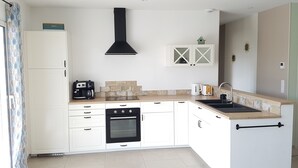 Una cocina moderna con armarios blancos, una estufa negra, una cafetera y un lavabo.