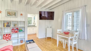Relax in this spacious living area with a high ceiling, featuring a mounted TV, dining table, and comfortable seating area.