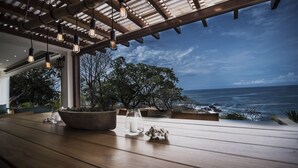 An outdoor seating area with a view of the ocean, wooden flooring, and potted plants. - Your Dream Costa Rica Villa - Ocean View Lap Pool - Private Chef-Secret Beach (Puerto Carrillo)