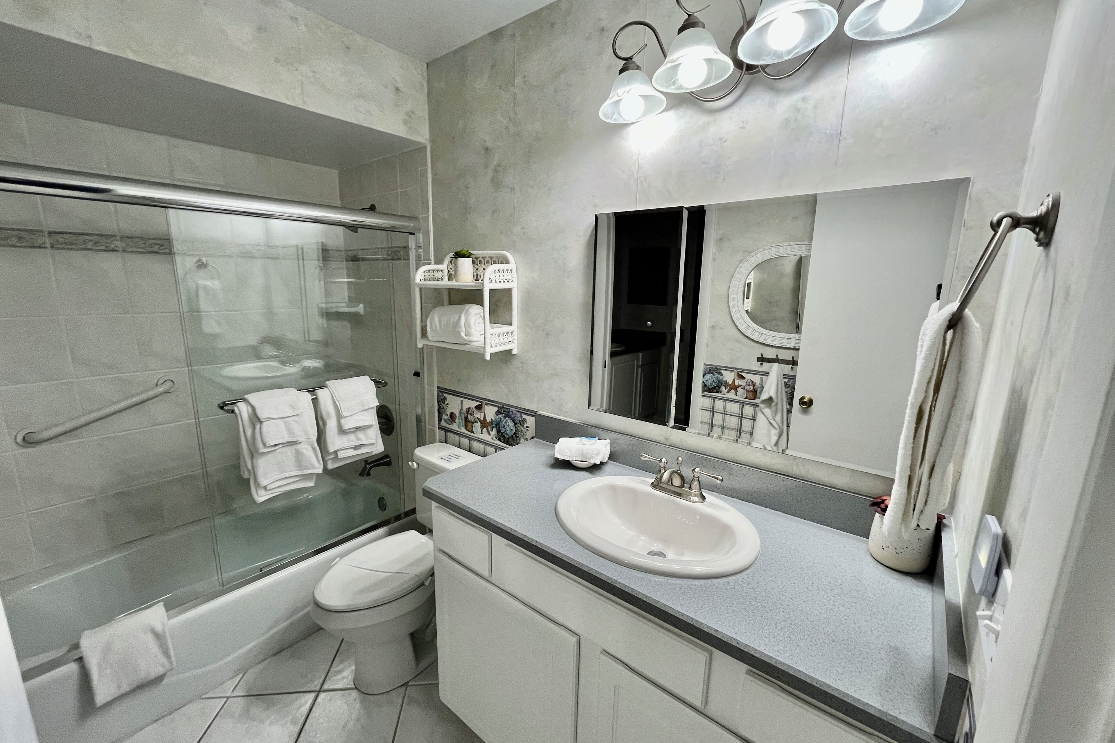 A modern bathroom with a glass-enclosed shower, a white toilet, a sink with a mirror above it, and a towel rack.