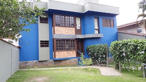 A modern two-story house with a blue exterior, large windows, and a small garden area. - Ground floor chalet 230 meters from Enseada Beach and 3 minutes from the sand. (UBATUBA)