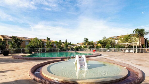 A swimming pool with a hot tub, surrounded by a tiled deck and a covered seating area.