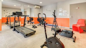 A gym with treadmills, elliptical machines, and a red chair.