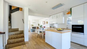 Una cocina moderna con armarios blancos, una isla central y un horno empotrado.