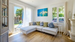 Una sala de estar moderna con un sofá seccional, ventanas amplias y un cuadro en la pared.