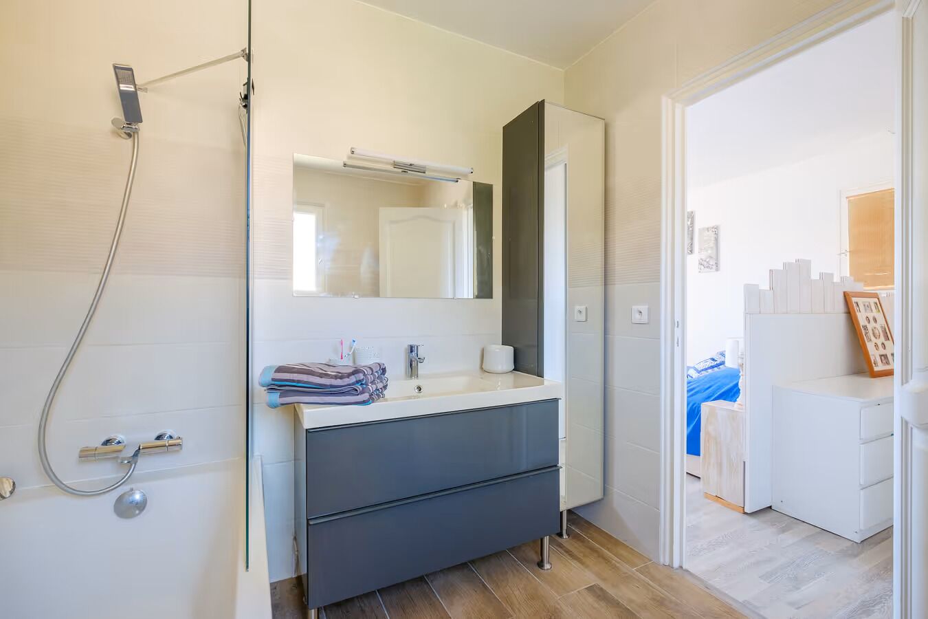 Ein modernes Badezimmer mit Dusche, Waschbecken, Spiegel und Waschtisch.