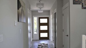 A hallway with a patterned rug, a ceiling light, and a door with a window. - Modern, new and close to lake (Lake Oswego)