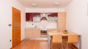 A modern kitchen with wooden cabinets, a stainless steel oven, and a dining table with chairs. - Villa Tucepi Apartment 5 (4+1) (Tucepi)