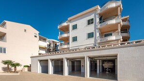 A multi-story building with balconies, a covered parking area, and a boat visible inside. - Villa Tucepi Apartment 5 (4+1) (Tucepi)